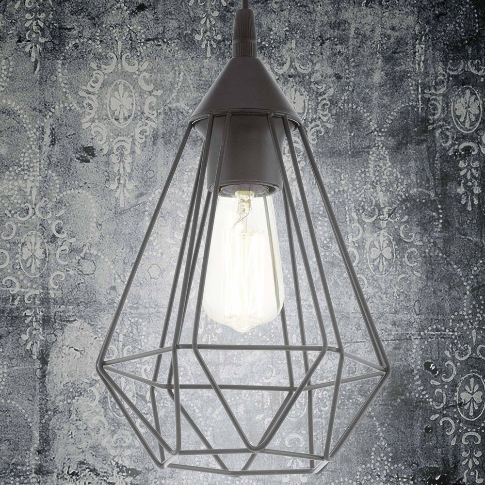 Una lampada a sospensione grigia con lampadina in gabbia geometrica su carta da parati fantasia.