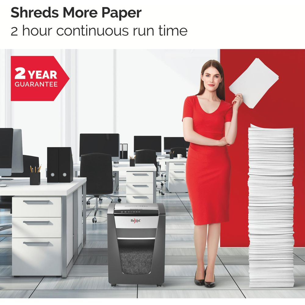 Femme en robe rouge à côté d'une déchiqueteuse et d'une pile de papier au bureau.