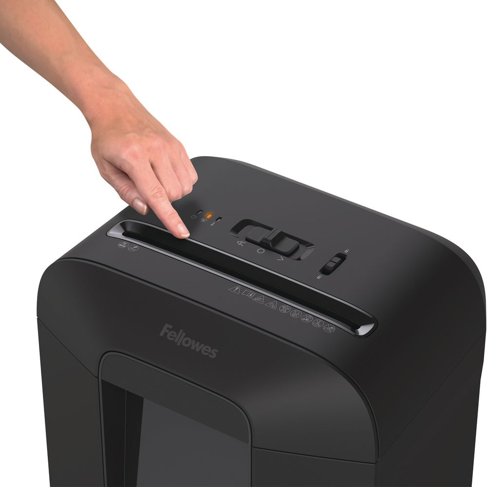 Eine Hand drückt einen Knopf auf einem schwarzen Fellowes-Aktenvernichter.