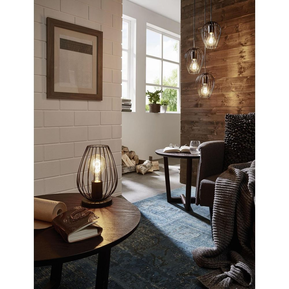Ein gemütliches Wohnzimmer mit einer Tischlampe, Hängelampen und einem Sessel mit Decke.