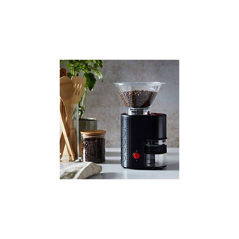 Czarny młynek do kawy ze szklanym zasobnikiem wypełnionym ziarnami.