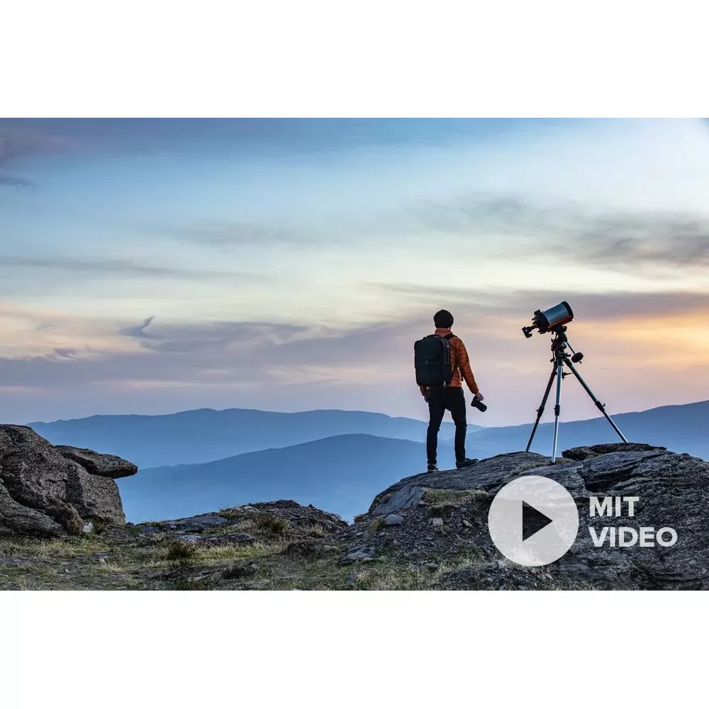 Mężczyzna z plecakiem stoi na skale i patrzy na teleskop.