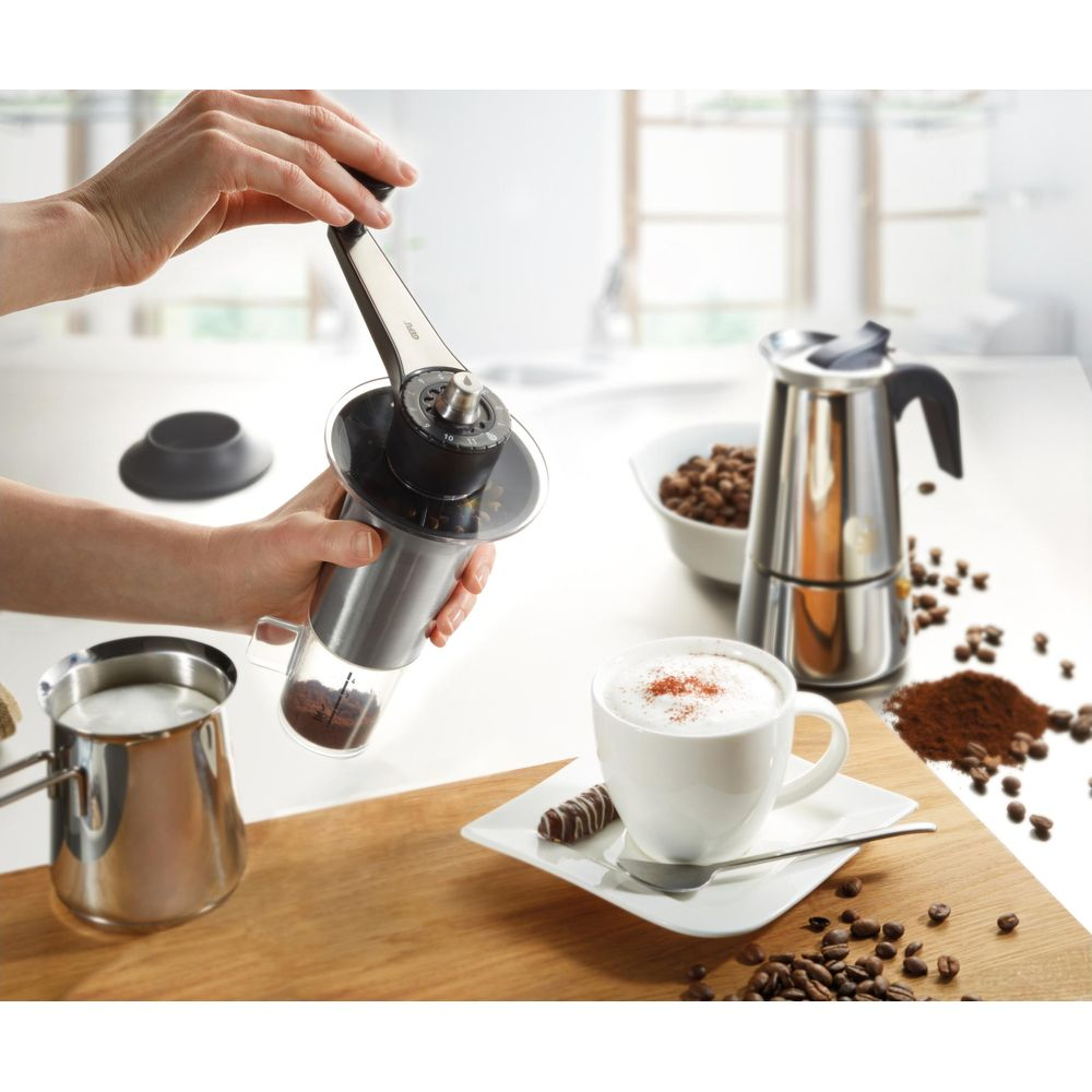 Kaffeemühle, Mokkakanne, Milchkaraffe und eine Tasse Cappuccino mit Zimt.