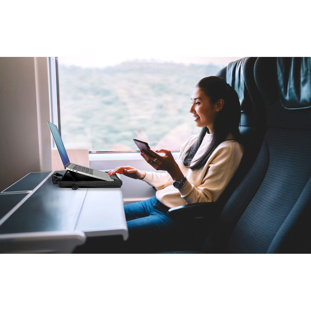 Donna su un treno usa laptop e telefono.