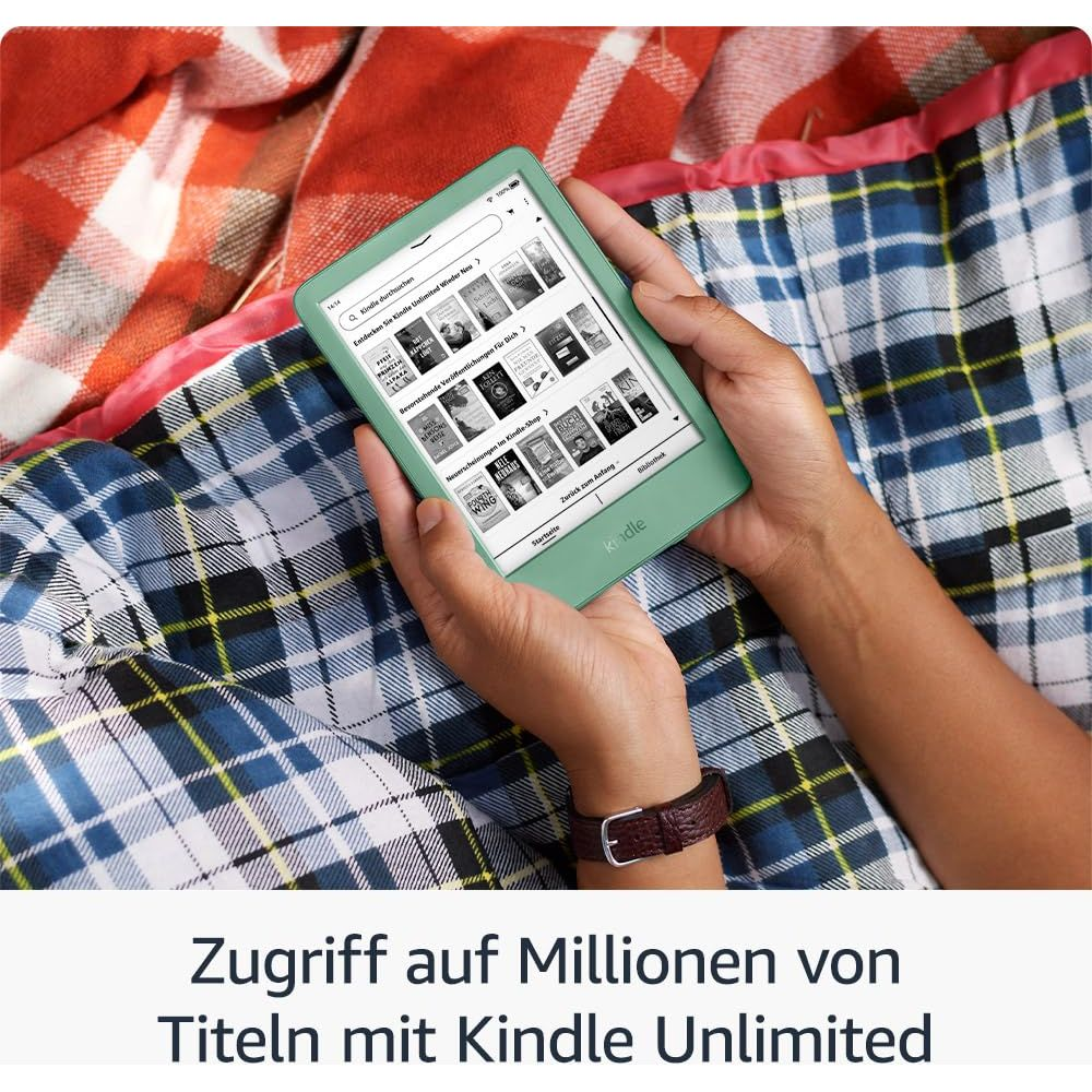 Zielony czytnik Kindle trzymany w dłoniach, leżący na kraciastych kocach. Widoczne okładki książek.