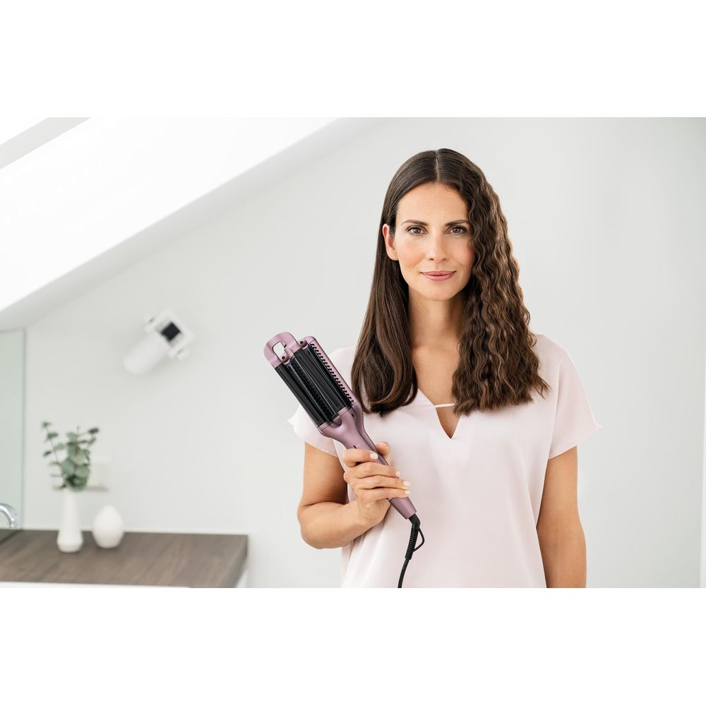 Eine Frau mit langen Haaren hält einen Lockenstab.