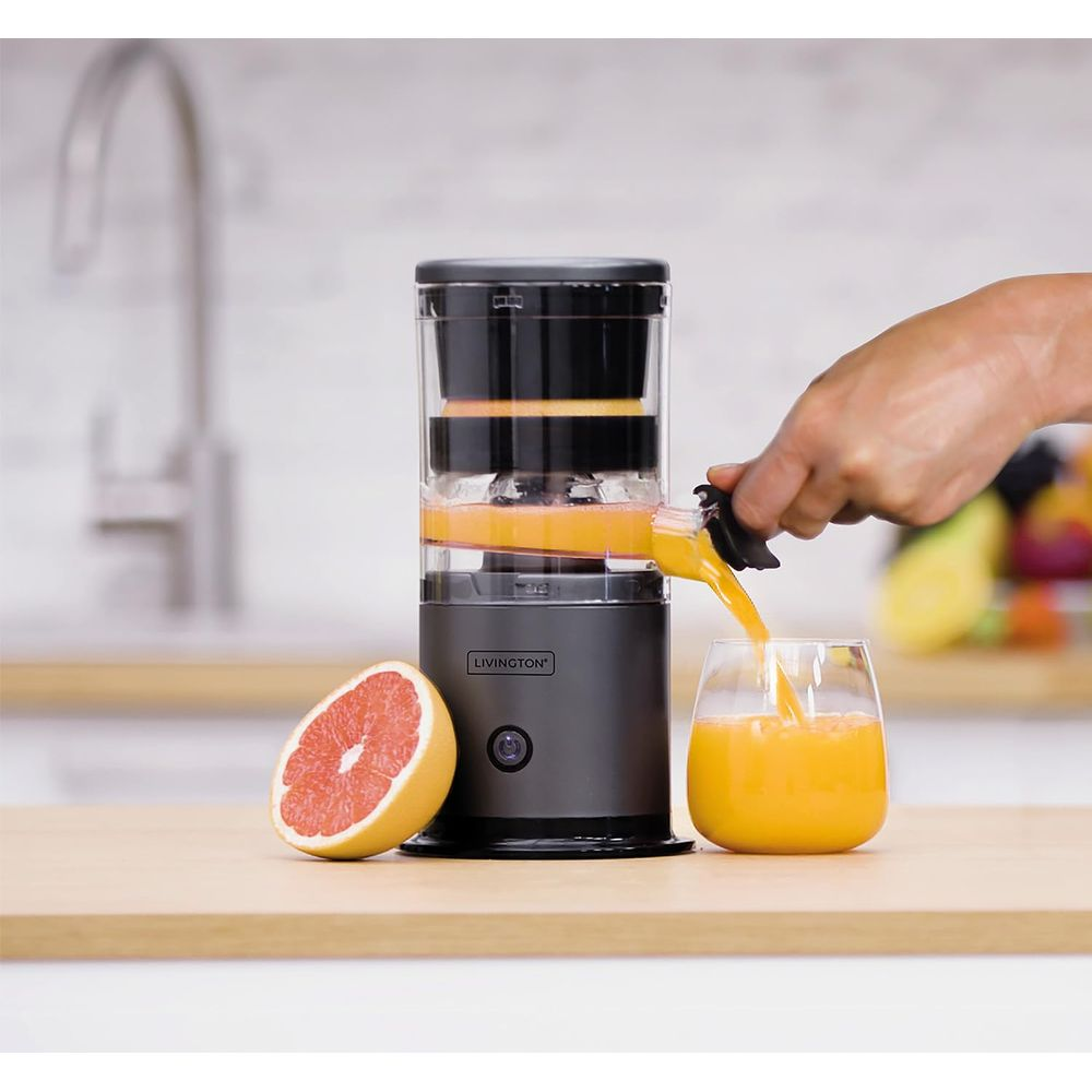 Eine Hand gießt frisch gepressten Orangensaft aus einem Entsafter in ein Glas.