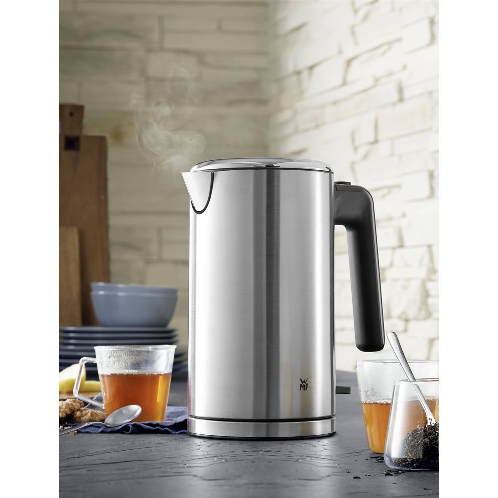 Srebrny czajnik z czarną rączką paruje na blacie kuchennym.