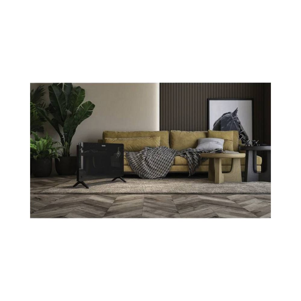 Ein schwarzer Heizkörper steht neben einem gelben Sofa, auf dem eine Decke liegt.