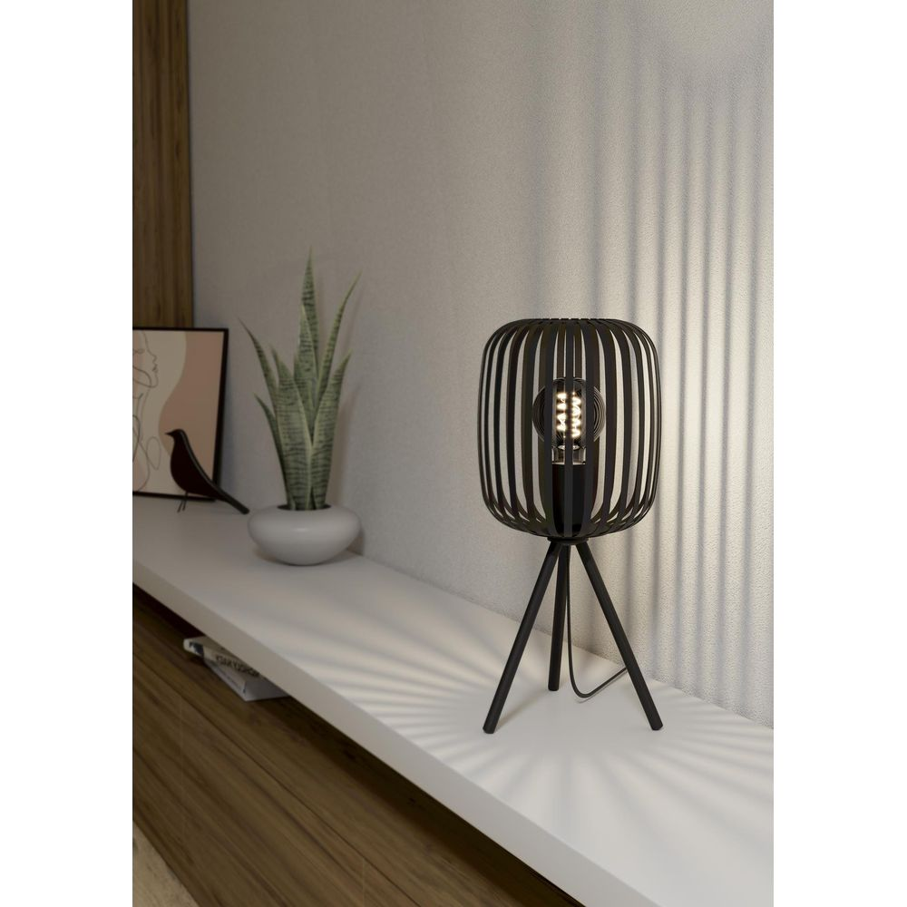 Een zwarte kooilamp met een lamp op een statief staat op een plank.