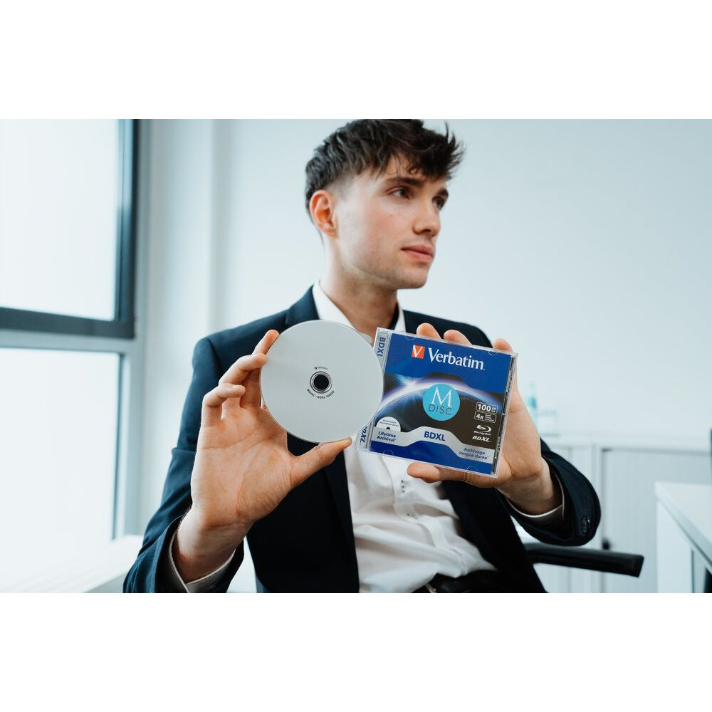 Mężczyzna w garniturze trzyma płytę Blu-ray i opakowanie płyt BDXL.