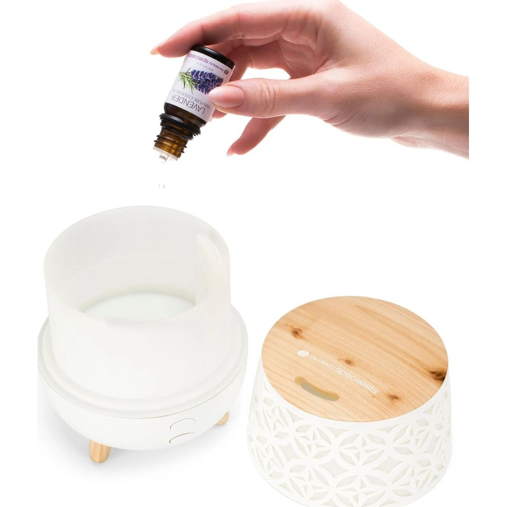 Una mano versa olio di lavanda in un diffusore.