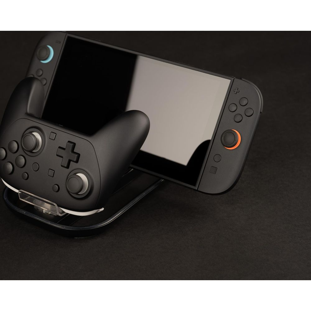 Controller di gioco nero collegato a una console portatile nera su una superficie scura.