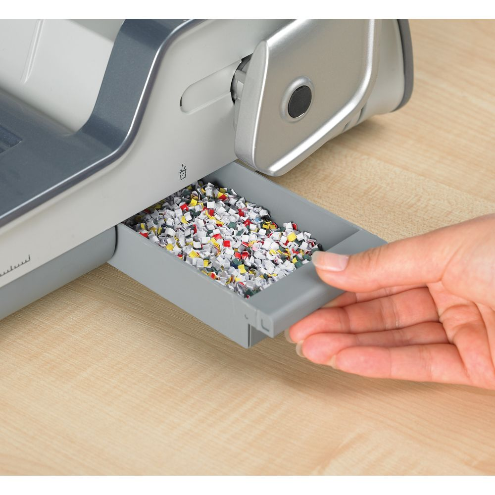 Eine Hand zieht eine Schublade mit zerkleinertem Papier voller Farben.