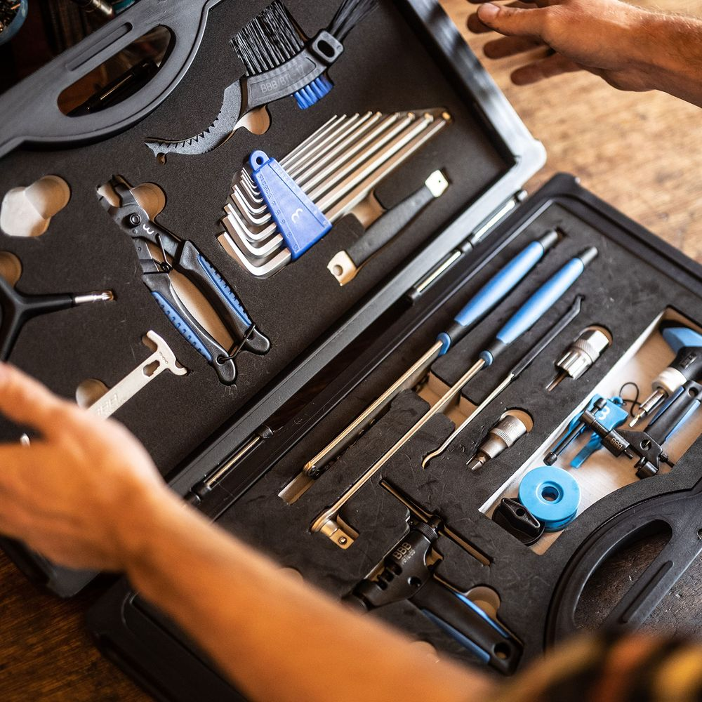 Skrzynka z narzędziami do naprawy rowerów, w tym klucze, szczypce i szczotki.