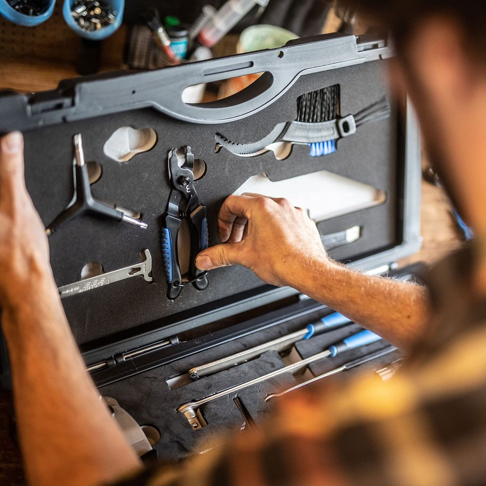 Ręka sięga po narzędzie do łańcucha w skrzynce z narzędziami.