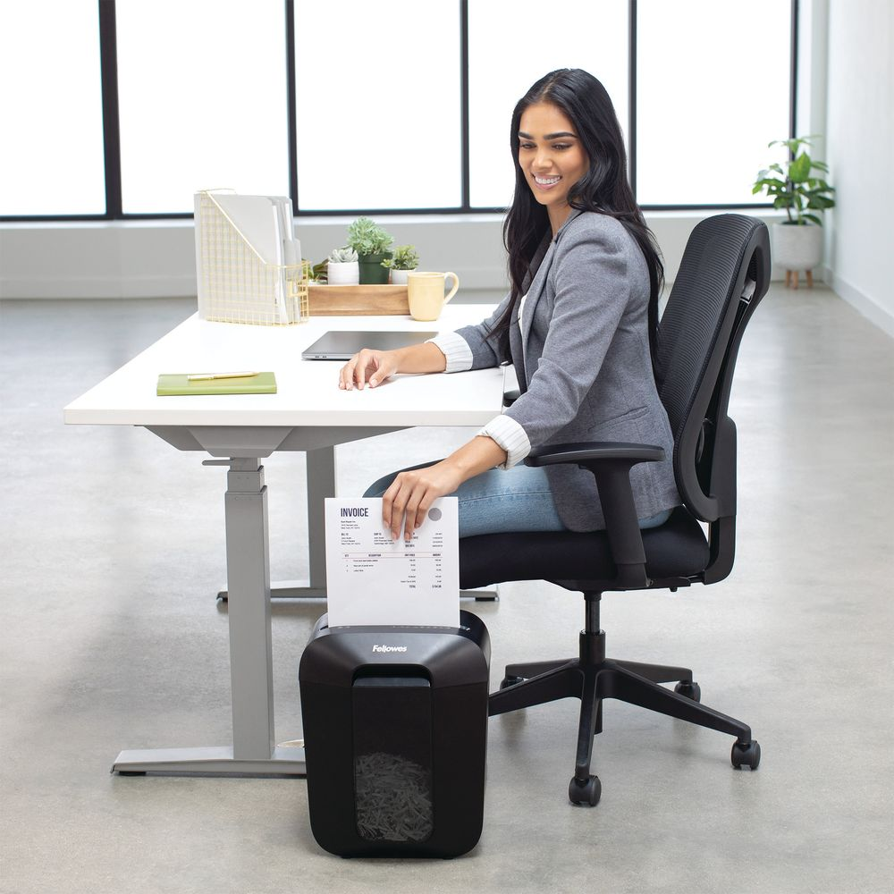 Une femme déchiquette un document à son bureau.