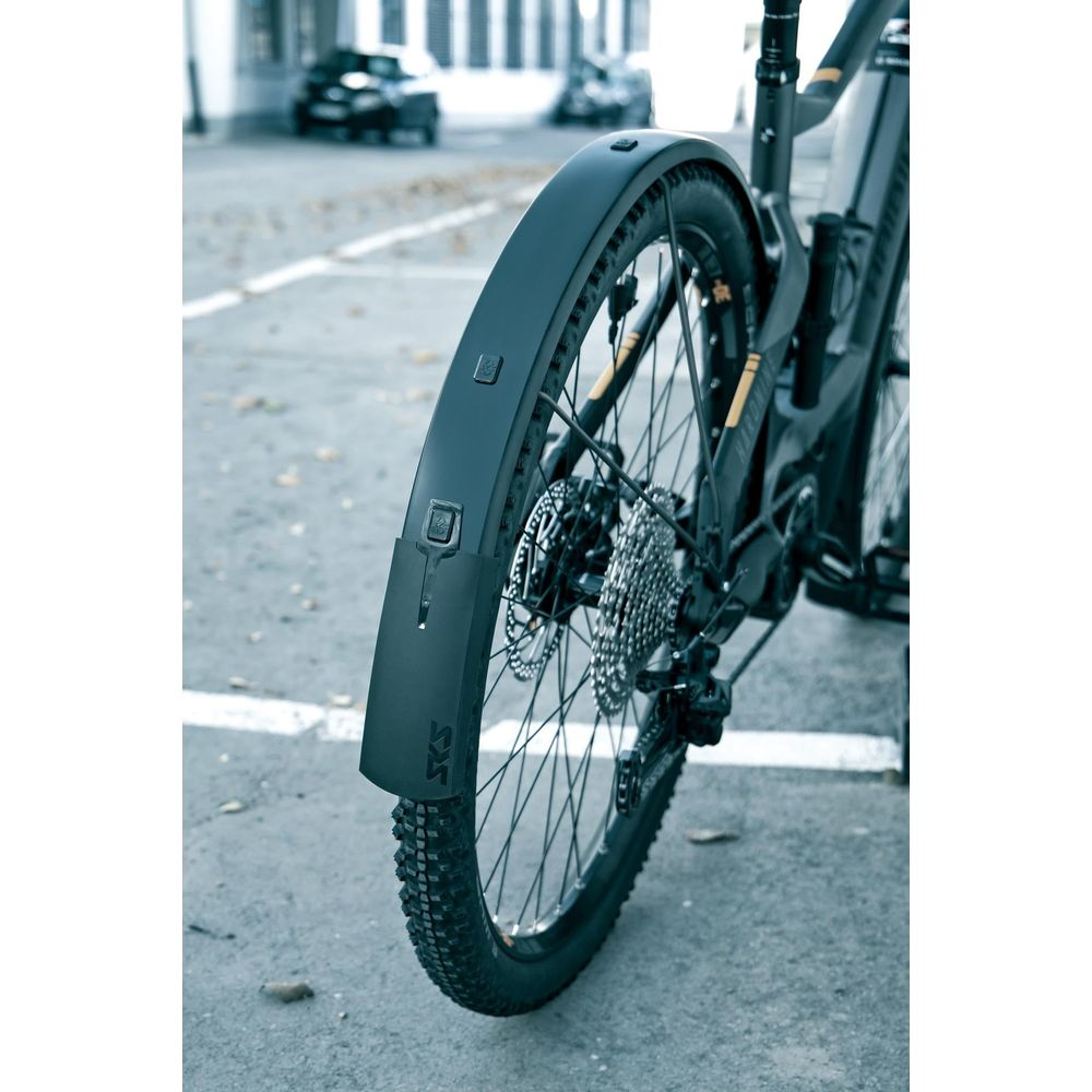 Zbliżenie tylnego koła czarnego roweru z błotnikiem i kasetą.