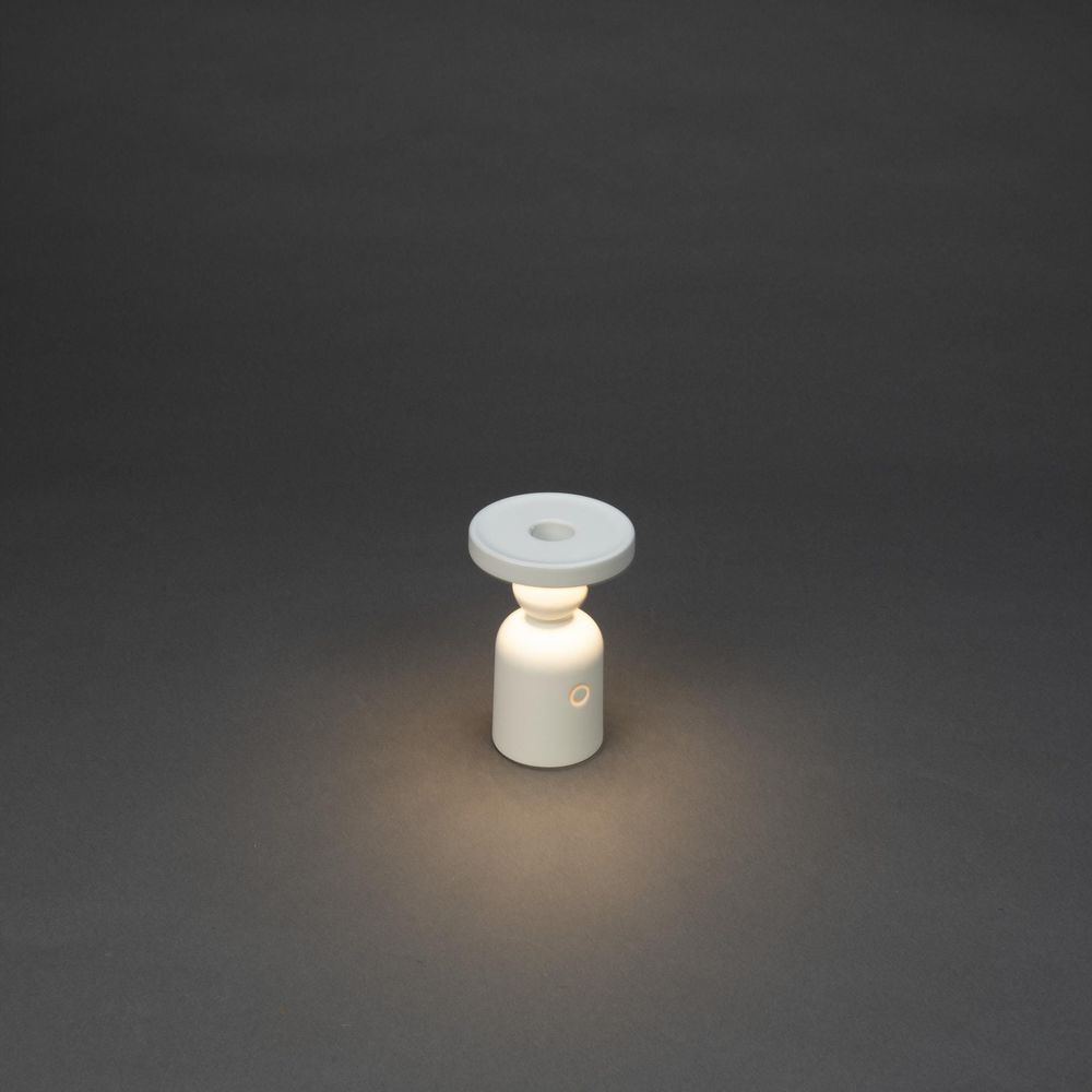 Eine weiße Lampe auf dunklem Hintergrund leuchtet.
