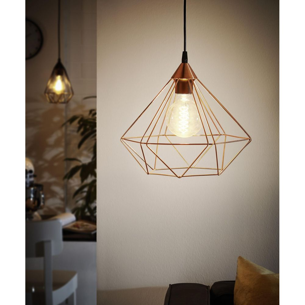 Una lampada a sospensione geometrica in rame con lampadina.