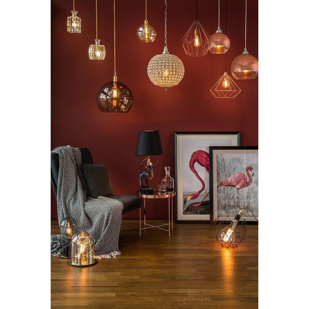 Una parete scura con lampade a sospensione, una poltrona con plaid, due quadri di fenicotteri e lampade.