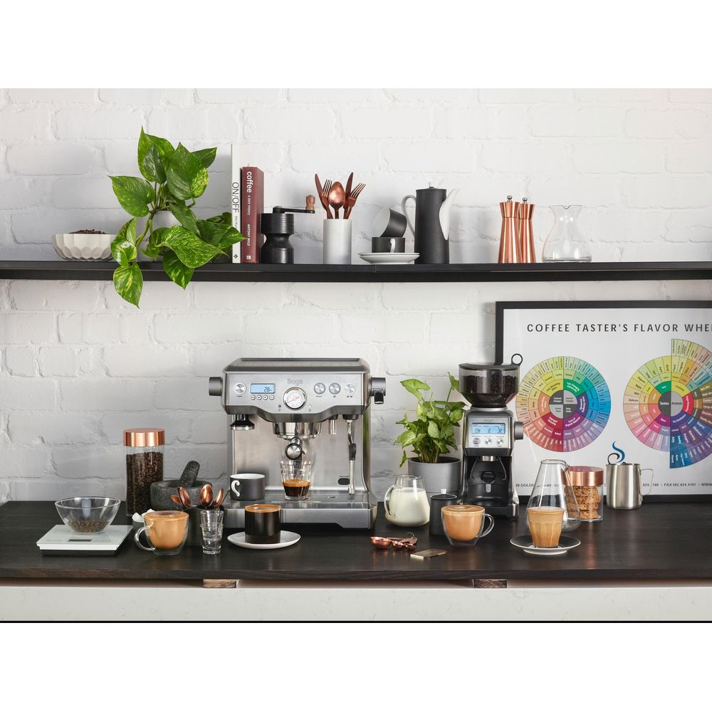 Eine Kaffeemaschine mit Zubehör auf einem dunklen Regal und einer Arbeitsplatte.