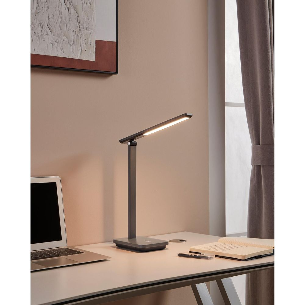 Ein moderner Schreibtisch mit Laptop, Lampe und Notizbuch.