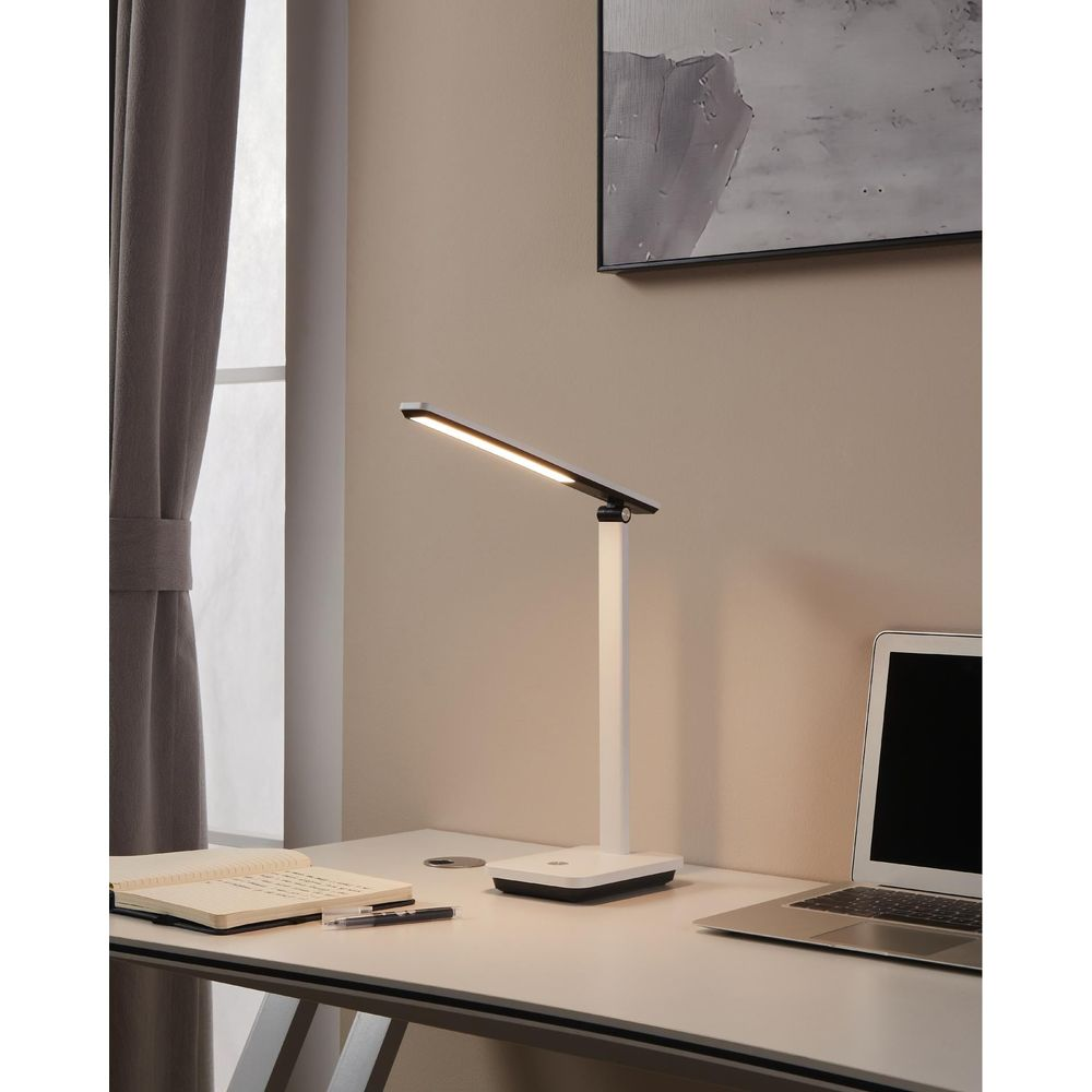 Ein moderner Schreibtisch mit einem Laptop, Notizbuch, Stift und einer LED-Schreibtischlampe.