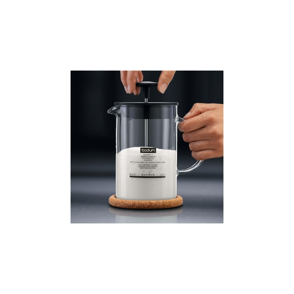 Spieniacz do mleka Bodum z białym mlekiem, trzymany ręką.