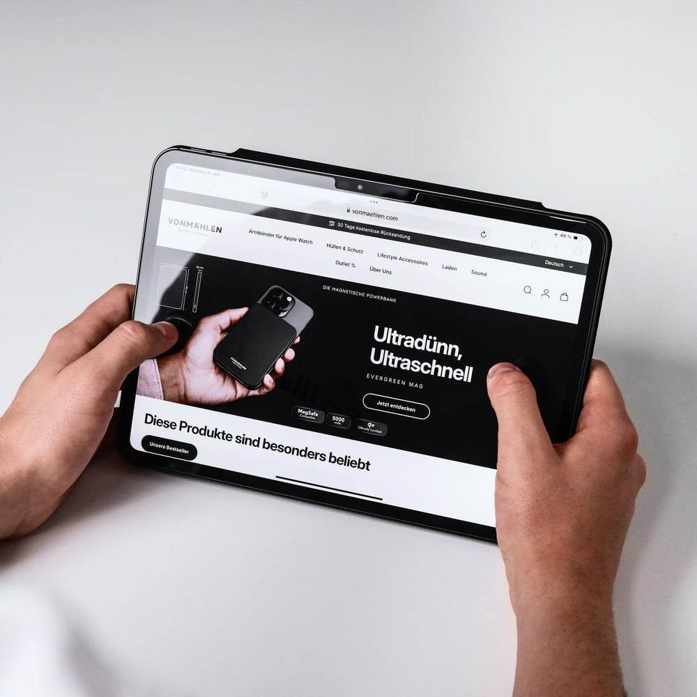 Persona tiene una tablet che mostra il sito vonMählen. Viene visualizzato un power bank.