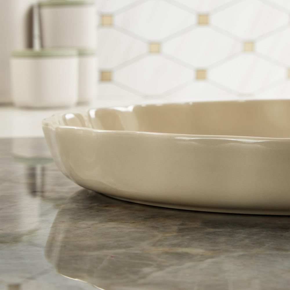 Kremowa ceramiczna miska z karbowaną krawędzią na marmurze.
