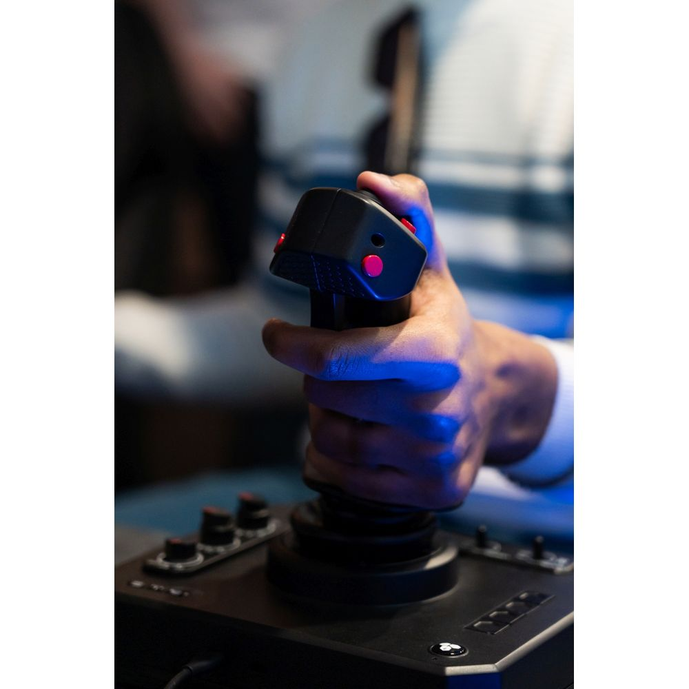A hand grips a black joystick with red buttons. Blue lighting.