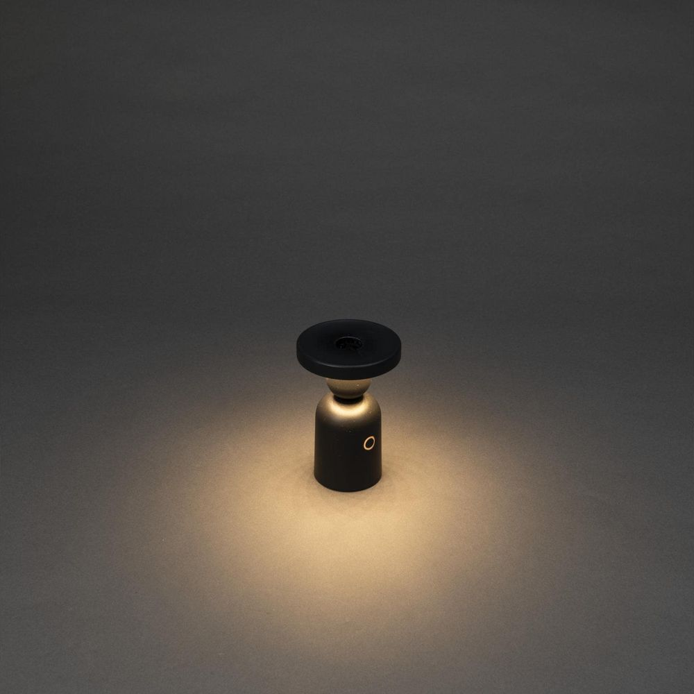 Eine schwarze, zylindrische Lampe mit einem oberen Ring und einem goldenen Kreis auf dem Körper.