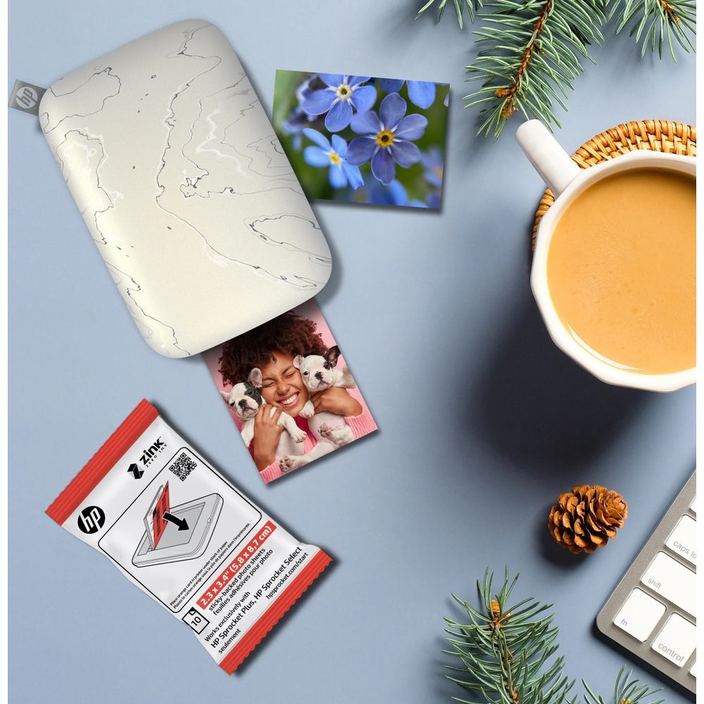 Biała drukarka HP Sprocket drukuje zdjęcie uśmiechniętej kobiety z dwoma szczeniętami.