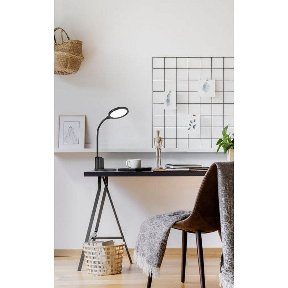 Ein Schreibtisch mit Lampe, Tasse, Korb und einer Decke auf einem Stuhl.