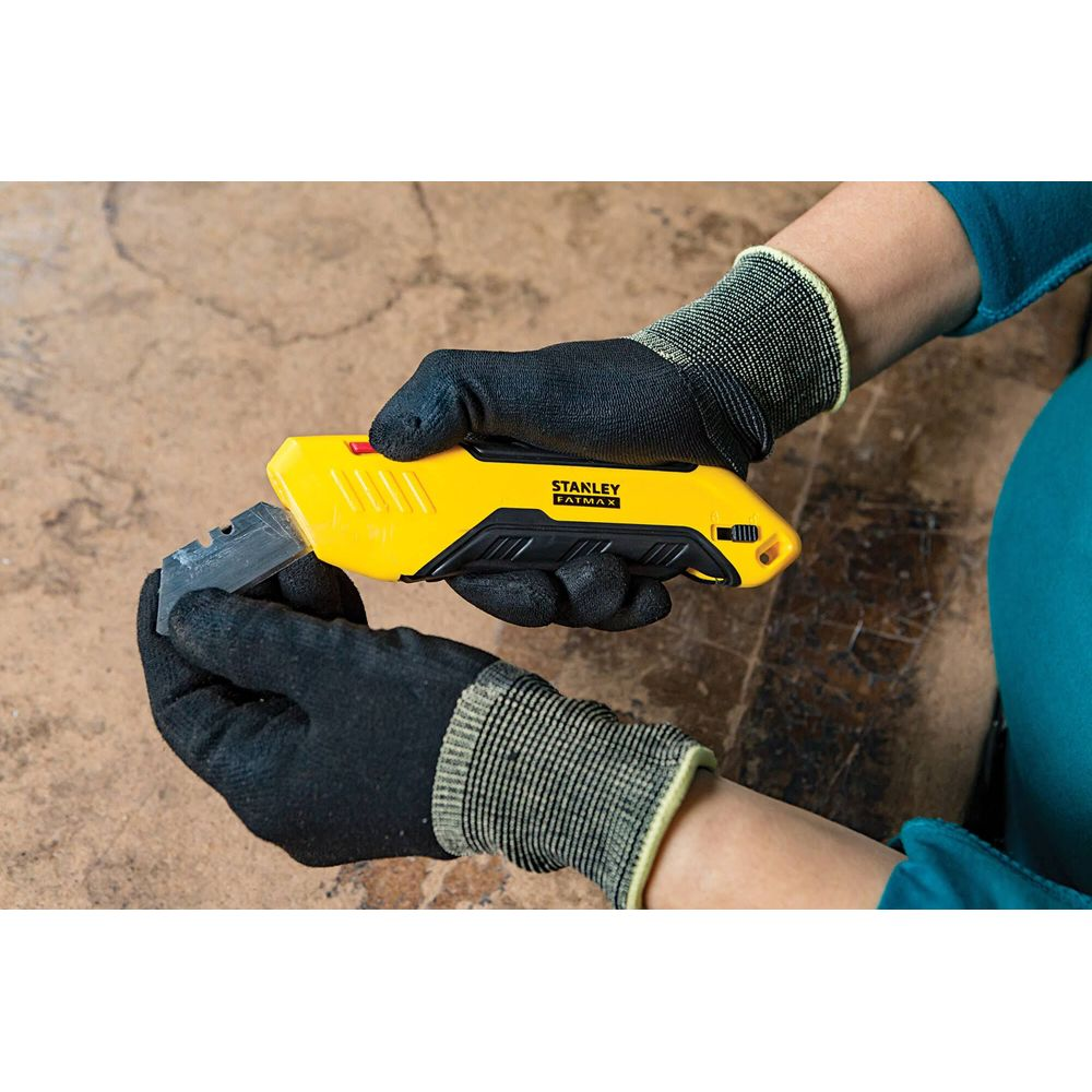 Persona con guantes cambia hoja en cúter Stanley amarillo.