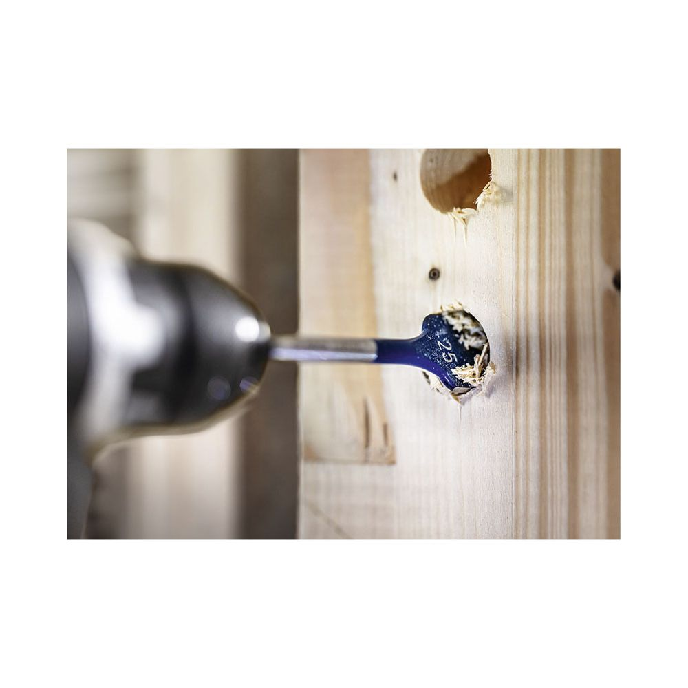 Wiertarka wierci otwór w drewnie, z trocinami.