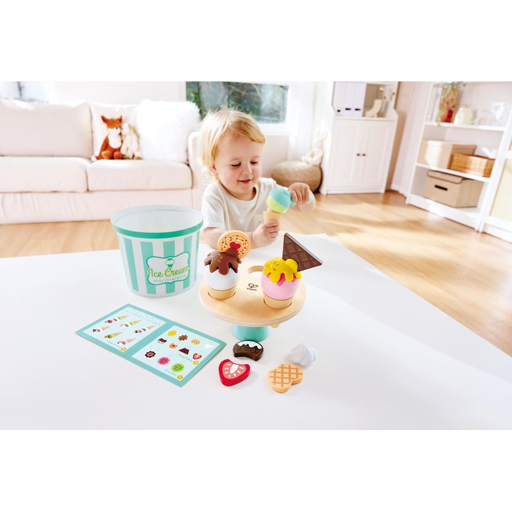 Ein Kind spielt mit einem Eiscreme-Spielzeugset auf einem Tisch.
