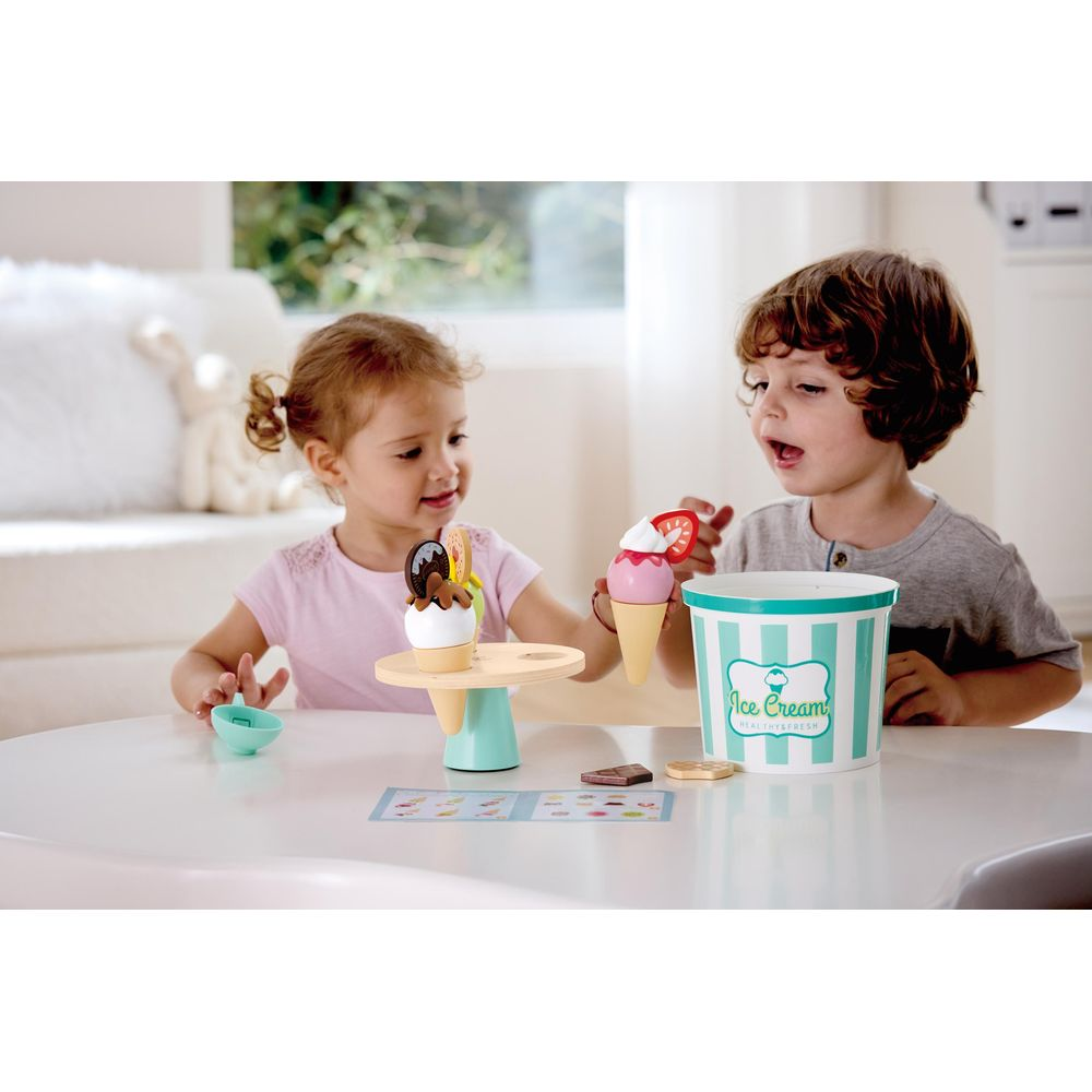 Zwei Kinder spielen mit Eiscreme-Spielzeug. Ein Junge hält eine Eiswaffel, ein Mädchen eine Eiscremestation.