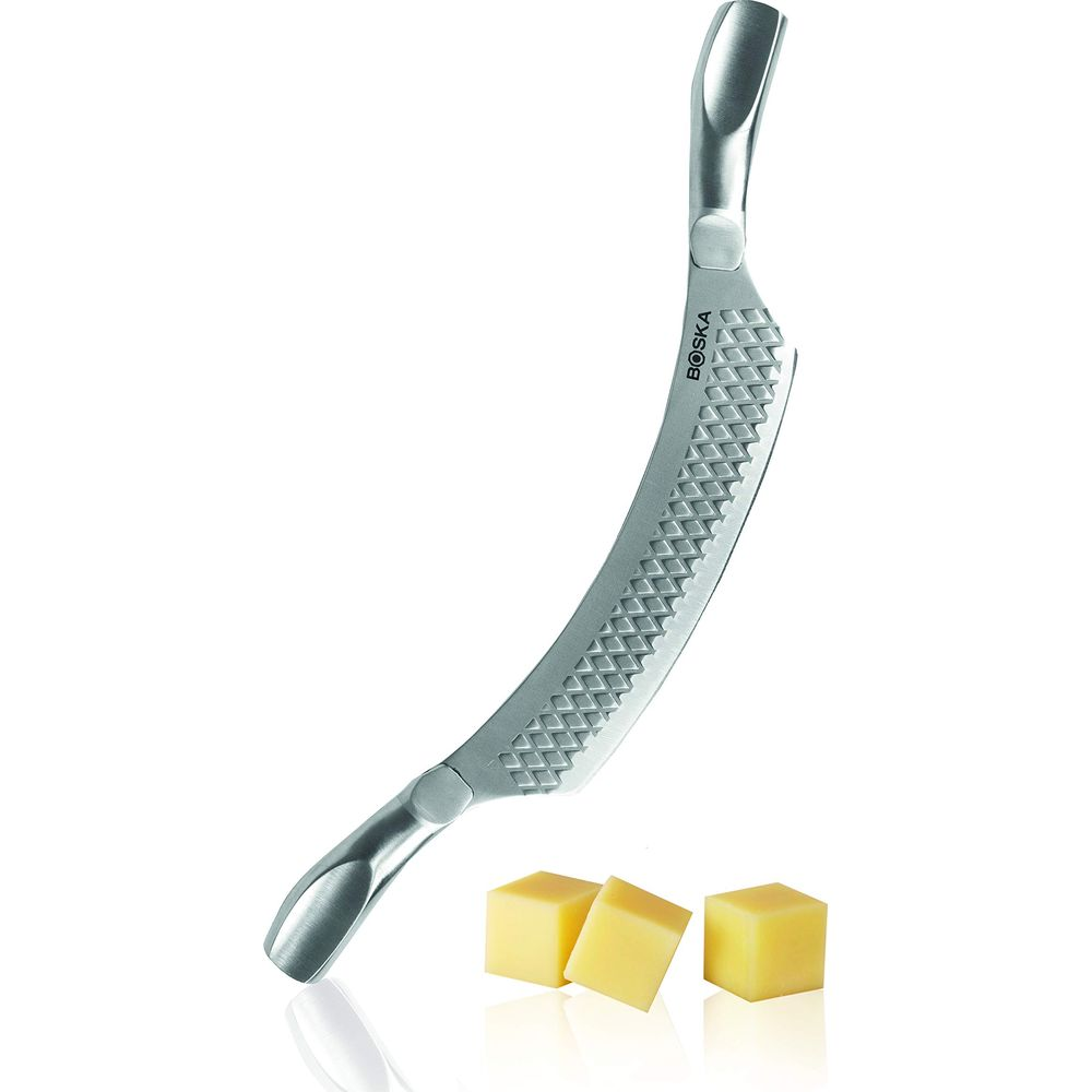 A curved metal cheese knife with three cheese cubes in front.
