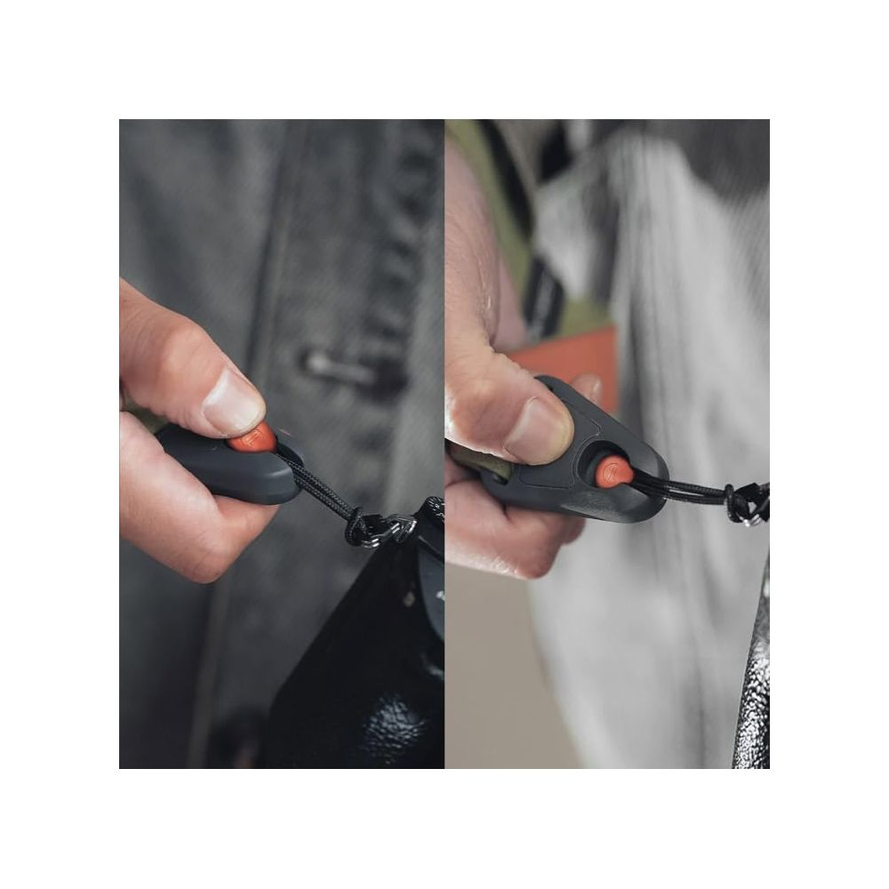 Dłoń trzymająca ciemny klips z czerwonym przyciskiem i czarnym sznurkiem.