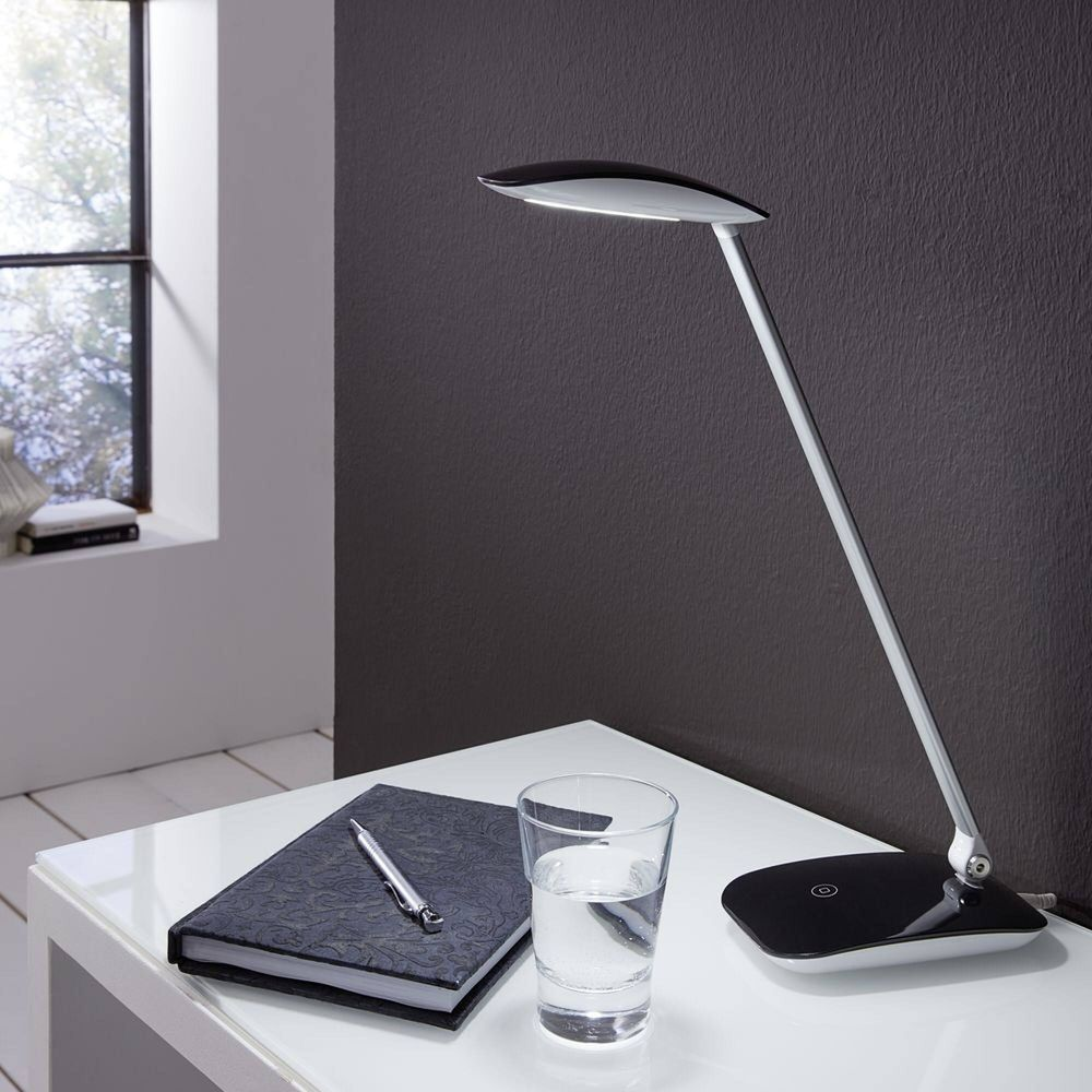 Una scrivania con lampada, taccuino, penna e bicchiere d'acqua.