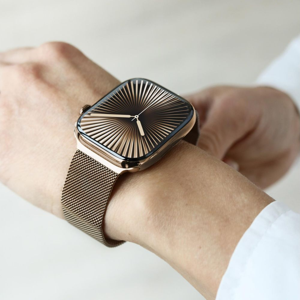 Eine goldene Smartwatch mit einem Sonnenstrahl-Zifferblatt an einem Handgelenk.