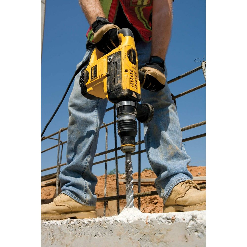 Ein Bauarbeiter bohrt mit einem gelben Bohrhammer in Beton.