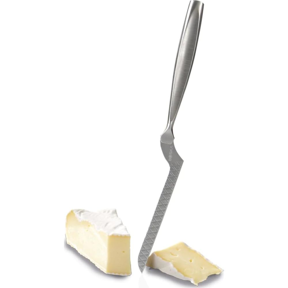 A cheese knife with a serrated blade cuts brie cheese into two pieces.