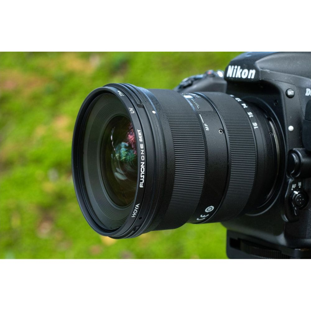 Eine Nikon-Kamera mit einem Weitwinkelobjektiv wird detailliert vor einem unscharfen grünen Hintergrund gezeigt.