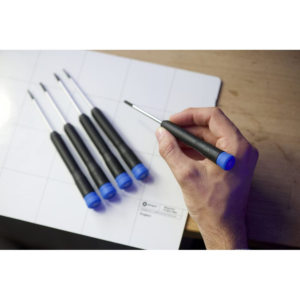 Cztery śrubokręty z czarnymi rękojeściami i niebieskimi końcówkami leżą na białej macie.