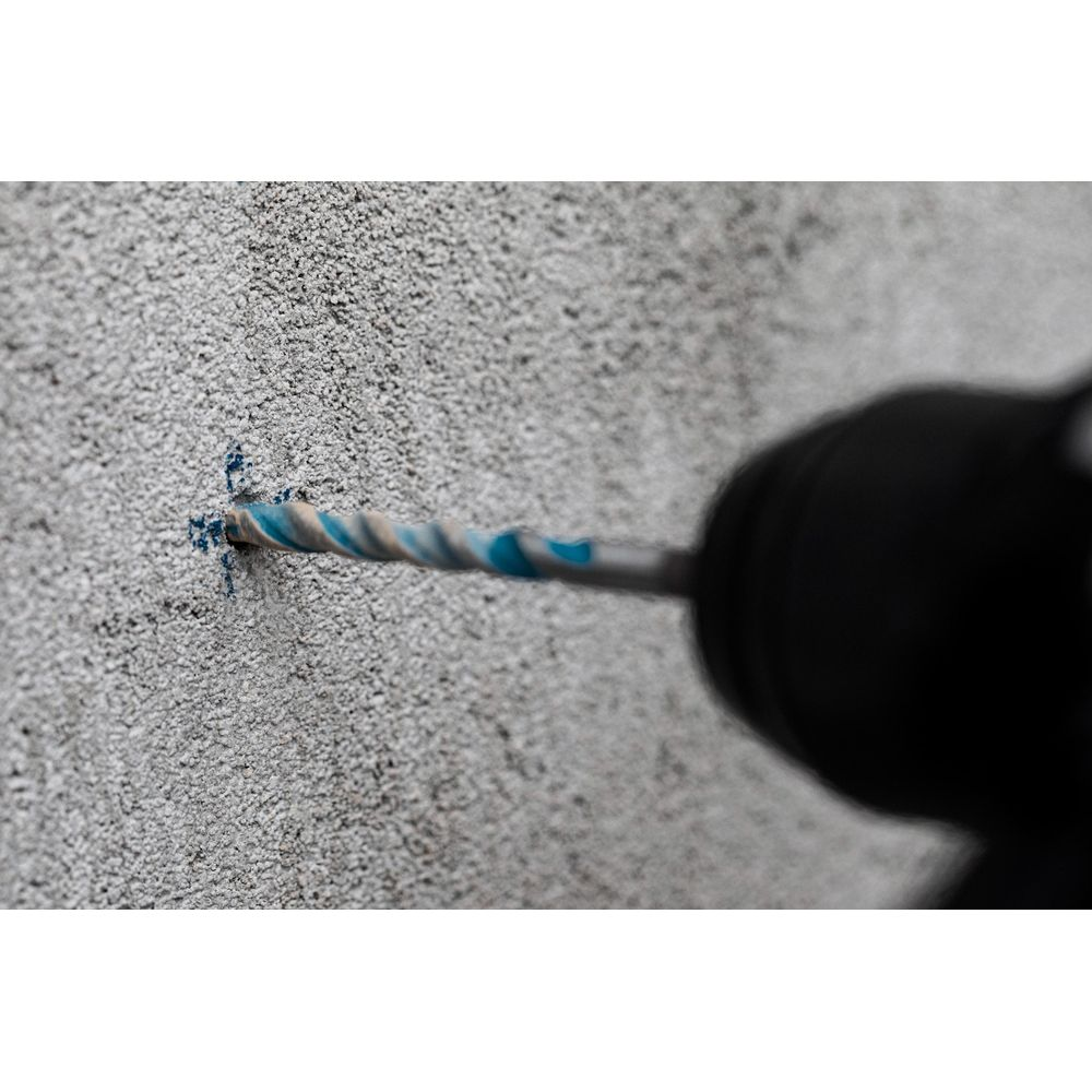 Bohrer mit blauen und weißen Streifen bohrt in eine graue Wand.