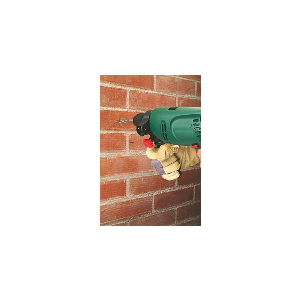 Une main gantée perce un trou dans un mur de briques.