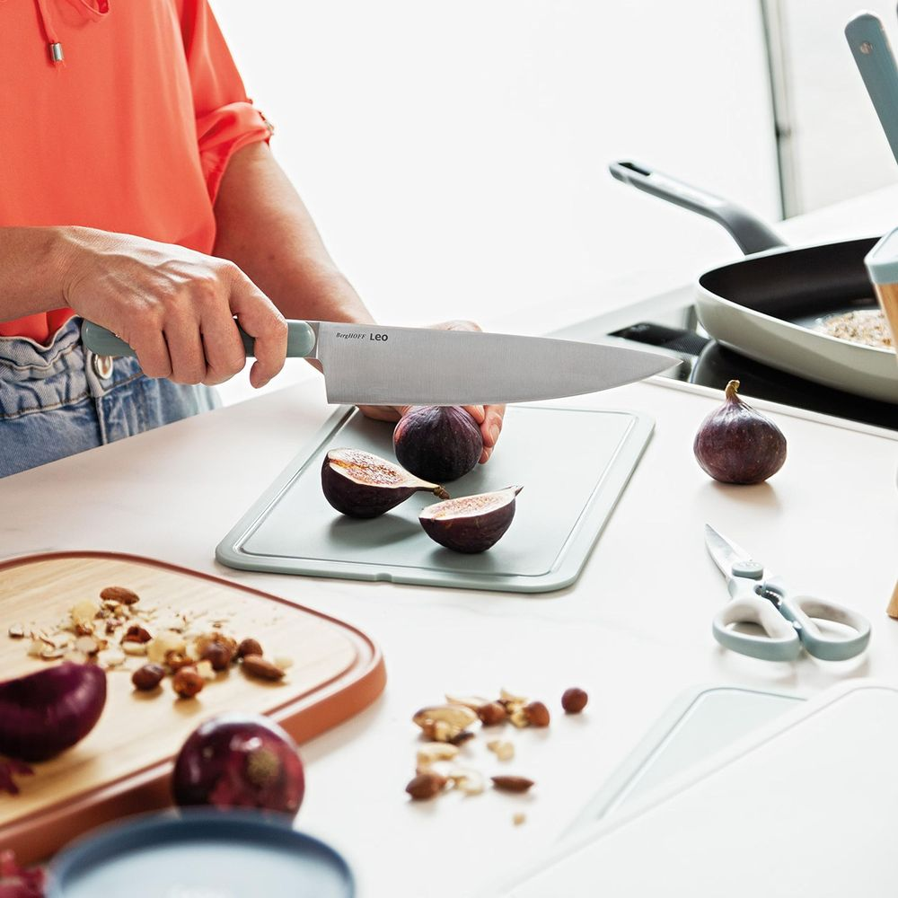 A person is cutting figs on a cutting board in a kitchen setting.